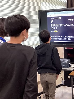 モニターを見て選挙について学ぶ生徒の写真